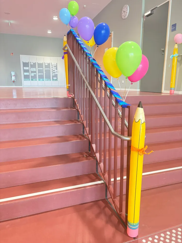 Bunte Luftballons und große gelbe Stifte schmücken das Treppenhaus